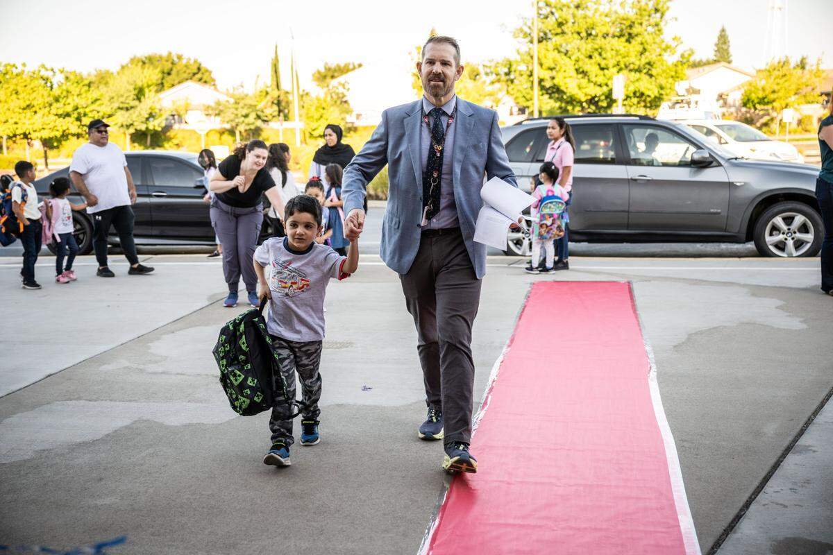 Navigator Elementary Principal James Tucker helps Amir walk down the red carpet on his first first day back to school Tuesday. The school's name is a reference to the Air Force flight navigators who once served at Mather Airport nearby.