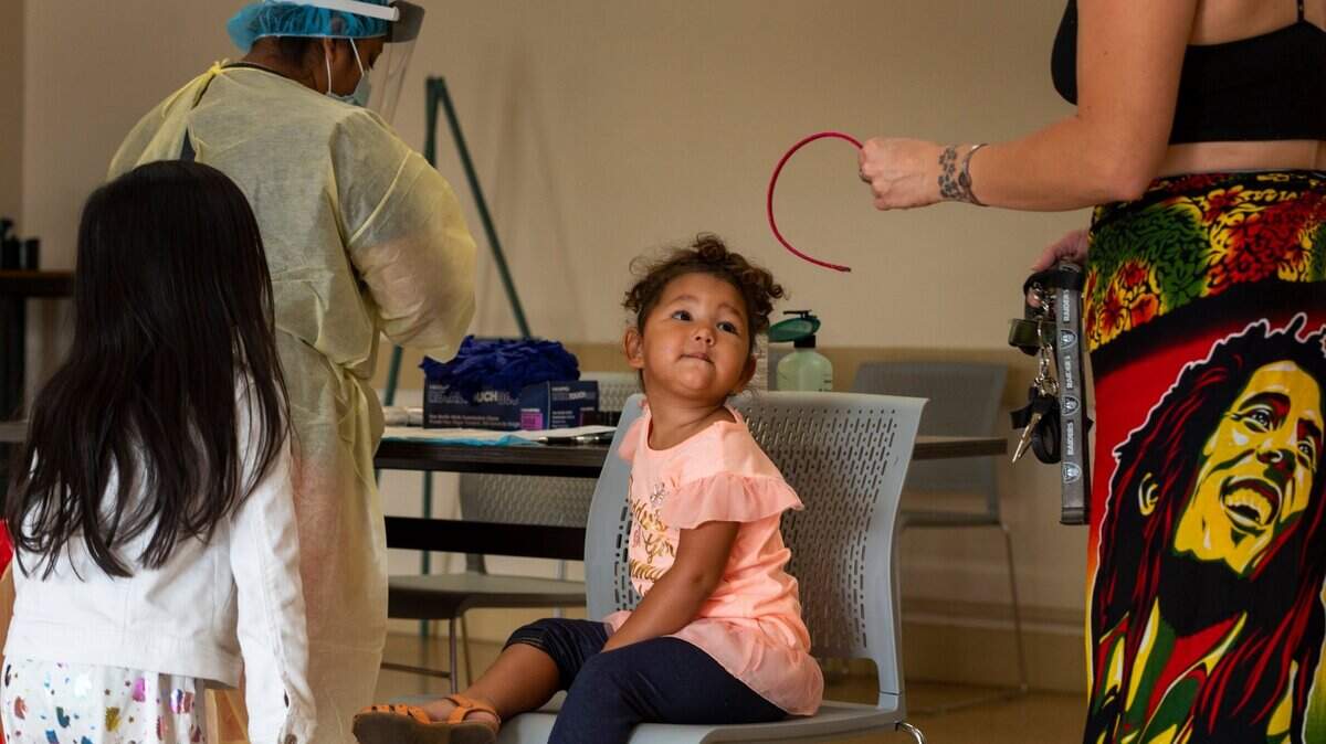 Zion Fontenot, 2, looks up at her mother Raphaella before a COVID test is administered by Maria Espinoza at Robertson Park Community Center in north Sacramento on Thursday, Sept. 17, 2020. All three siblings were tested.