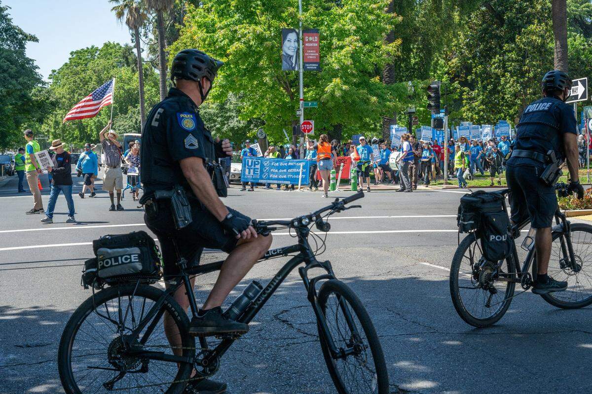 Police on bicycles wait as striking University of California health care, research and technical workers depart Sacramento’s Fremont Park and take to the streets in protest on Thursday, May 1, 2025. Several hundred workers joined the march against the university’s hiring freeze. 