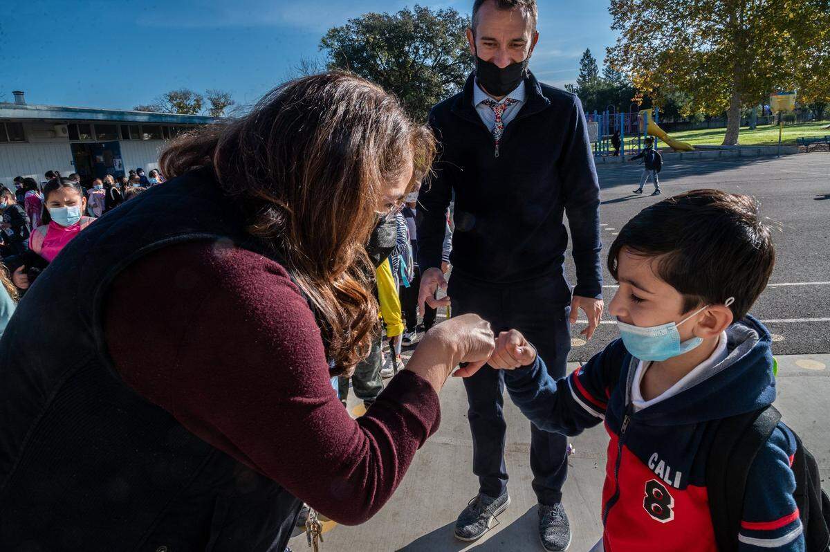 Raihan, 6, fist bumps with his first-grade teacher Rosa Marquez after Principal Nate McGill walked him over to her at Ethel I. Baker Elementary School in Sacramento on Monday. It was Raihan’s first day back to school after being stranded in Afghanistan with his family after the Taliban takeover of the country.