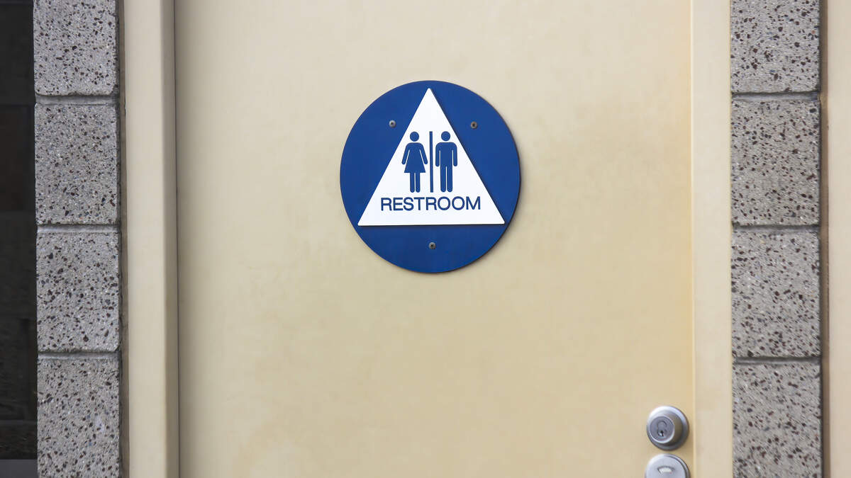 A sign on the door of a public restroom indicates that it is available for all genders. 