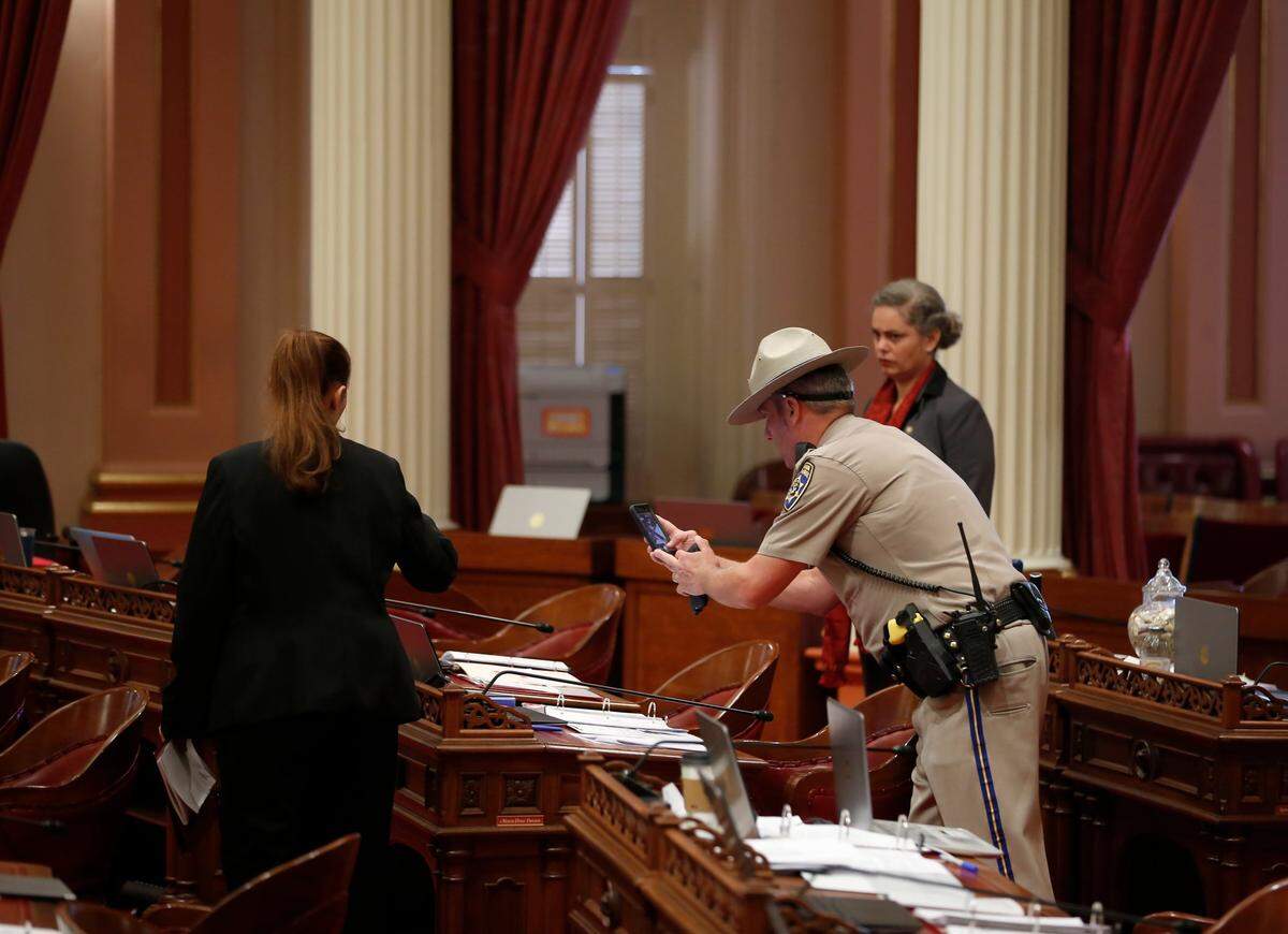 A California Highway Patrol Officer photographs a desk in September 2019 on the Senate floor after blood was thrown from the Senate gallery while lawmakers were conducting business, at the state Capitol.