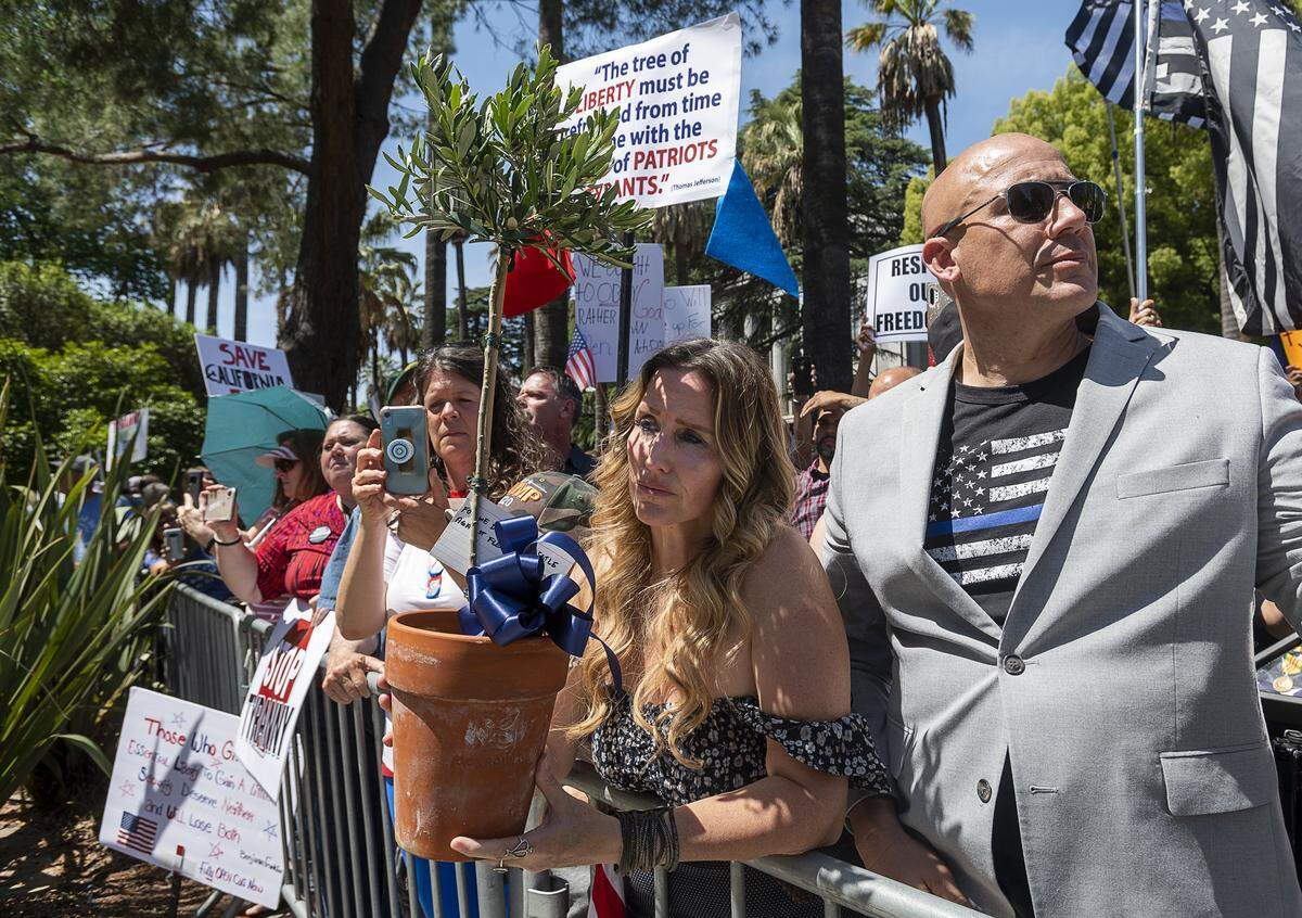 Tara Thornton of the Freedom Angels holds an olive tree for law enforcement officers with Tim Thompson, a conservative pastor from Riverside County, during a protest at the state Capitol on Thursday, May 7, 2020 in Sacramento during the coronavirus pandemic.