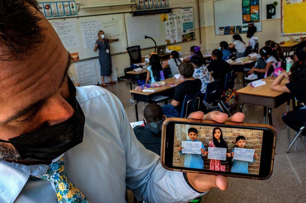 Ethel I. Baker Elementary School Principal Nate McGill holds his cell phone Thursday showing a picture sent to him by the family of three students stranded in Afghanistan, as he stands in one of their classrooms on the first day of school. The children, who traveled with their mother to visit an ailing family member, are now in hiding.