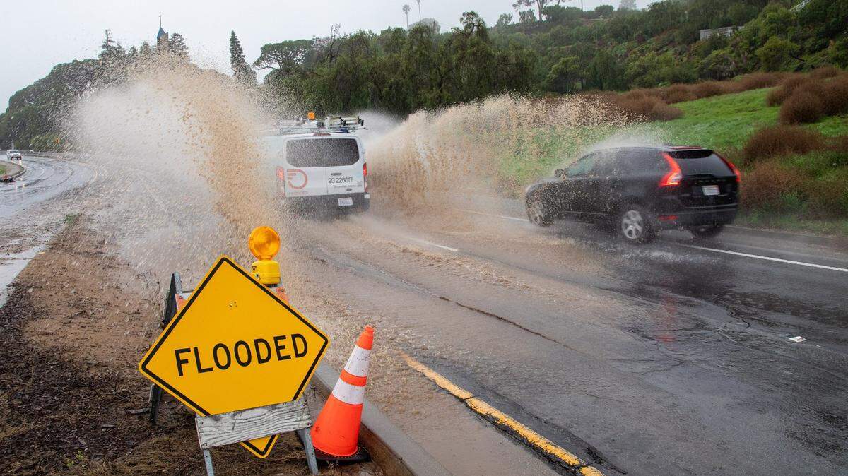 Vehicles drive drive on a flooded street in Los Angeles in 2023. CEQA reform could accelerate climate adaptation across California by cutting lengthy environmental reviews for levees, wetlands and other urgent projects.