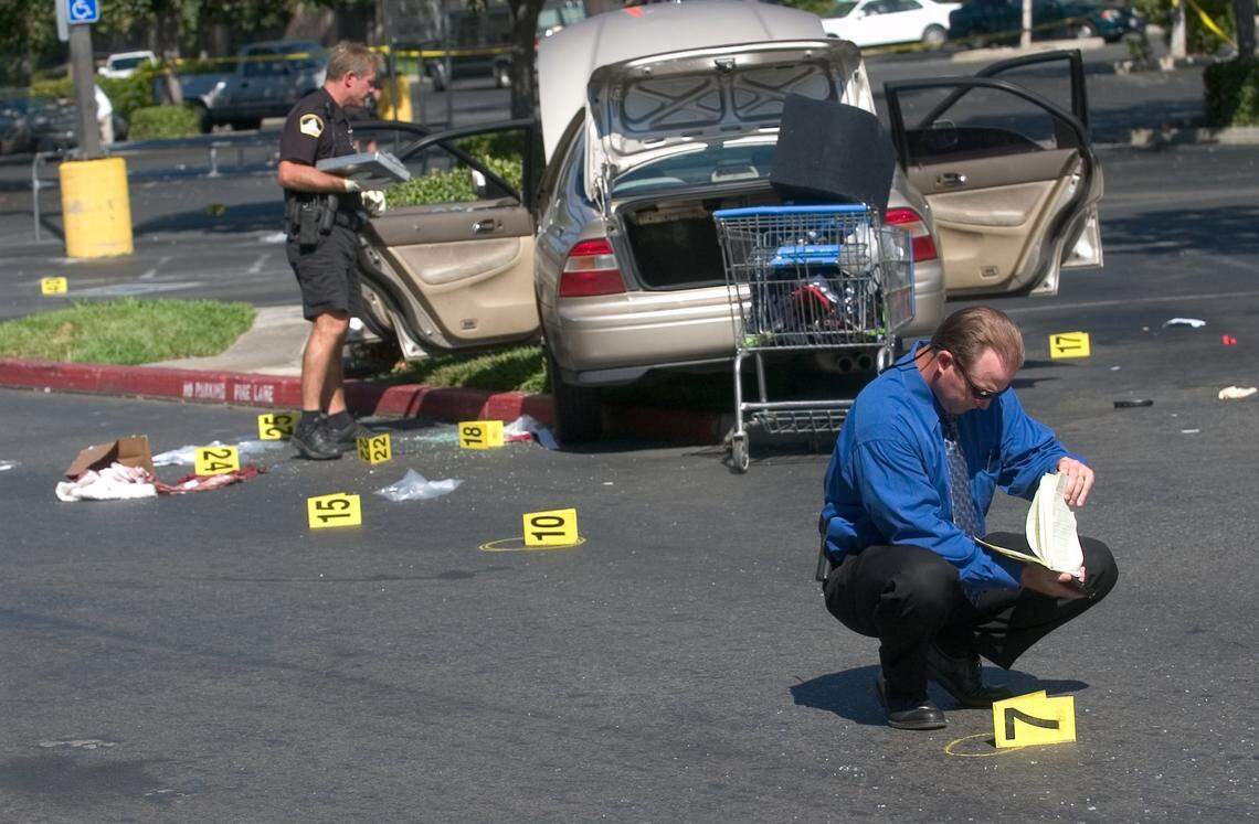 Sacramento police homicide Sgt. Craig Hill, foreground, looks over the crime scene of a gang shooting that occurred in the Albertson’s parking lot at the corner of Power Inn Road in August 2005. Three people were killed and two others wounded.