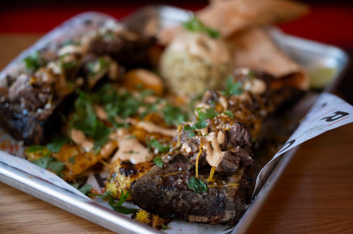 A bone marrow “Charplate,” served with rice and grilled squash and covered in chili lime seasoning, sits on a table at Char Market in Carmichael on Thursday, Aug. 28, 2024.