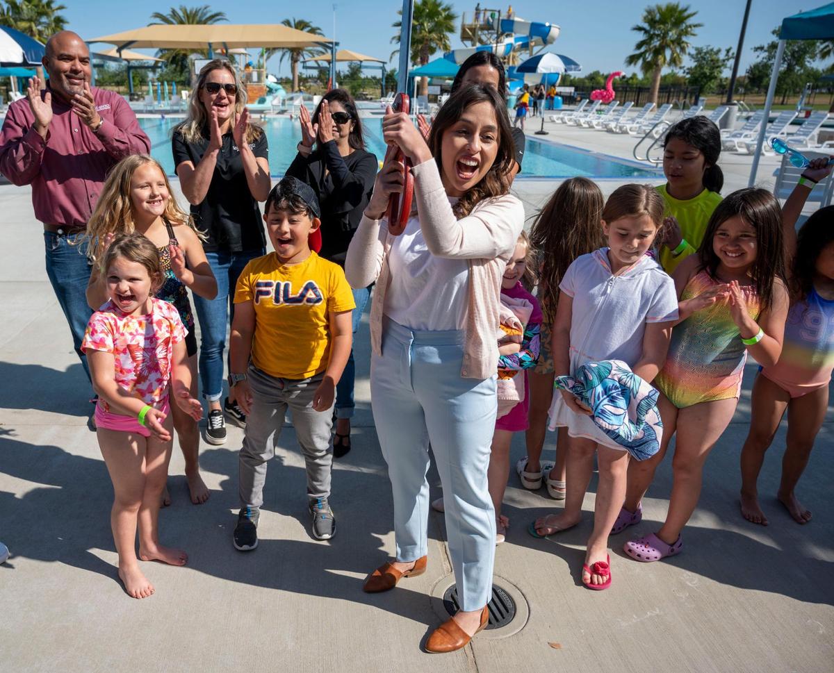 Karina Talamantes, chief of staff for Sacramento City Councilwoman Angelique Ashby, holds a giant pair of scissors after cutting the ribbon for the official grand opening of the North Natomas Community Center and Aquatics Complex on Saturday, April 23, 2022.
