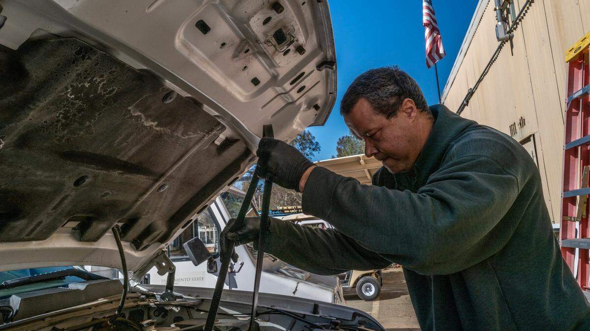 Matt Mason, an automotive service technician, changes a fan belt on one of 300 vehicles he helps maintain at Sacramento State on Monday, Feb. 6, 2023. He has worked as a campus steward for Teamsters Local 2010 for 17 years and at the university for 20. “The only way for us to get a raise is to pull a lateral and get another job,” said Mason who would prefer to stay on campus.