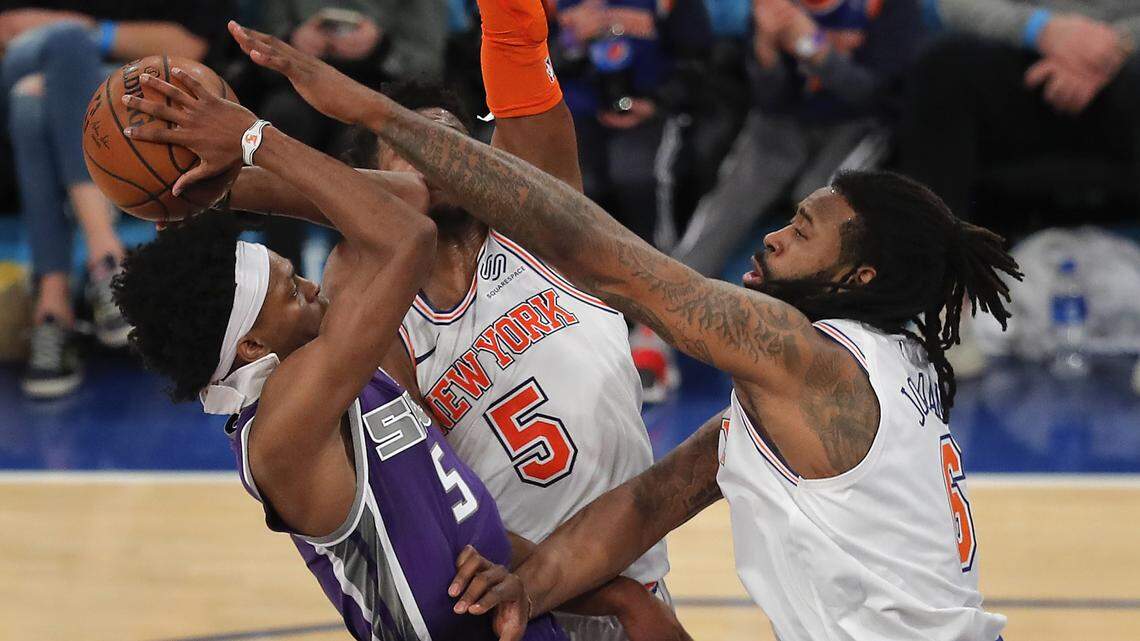 Kings guard De’Aaron Fox puts up a shot against New York Knicks center DeAndre Jordan, right, and guard Dennis Smith Jr. (5) on Saturday in New York.