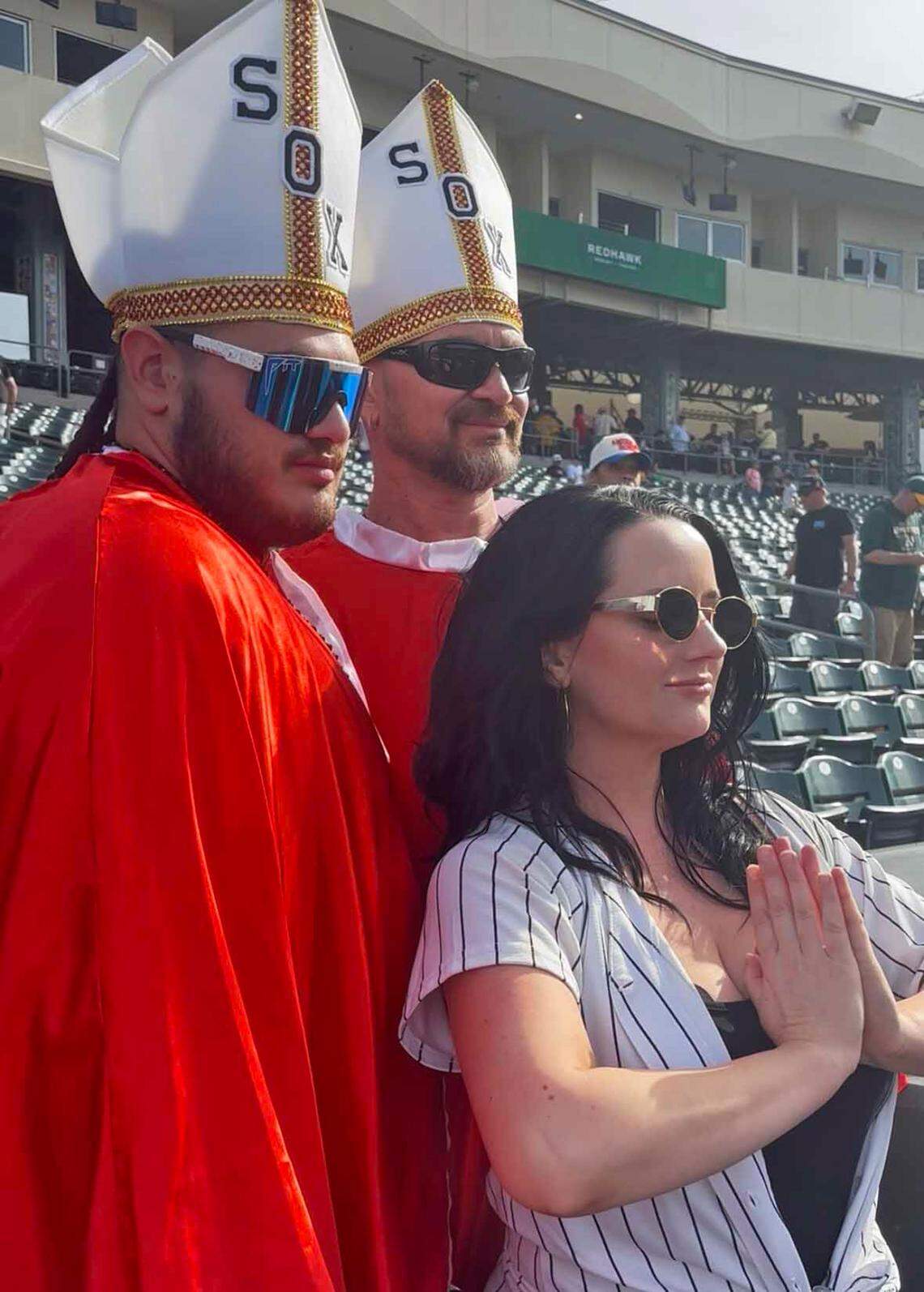 A woman poses with Oscar and Tristan Perez, dressed in papal garb, during an Athletics game against the Chicago White Sox in West Sacramento on Saturday.