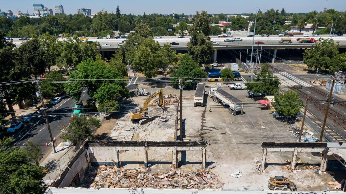 Crews work on demolition on the property at 19th Street and Broadway, south of X Street and west of the rail tracks, on Tuesday, seen in a drone photo July 18, 2023, in Sacramento. The long-vacant office building is being demolished to make way for a 140-unit affordable housing apartment building.