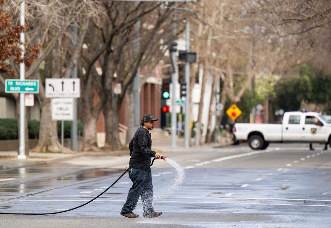 A crew member wets down H Street, closed for filming, in downtown Sacramento in preparation for a scene in director Paul Thomas Anderson’s upcoming movie on Saturday.