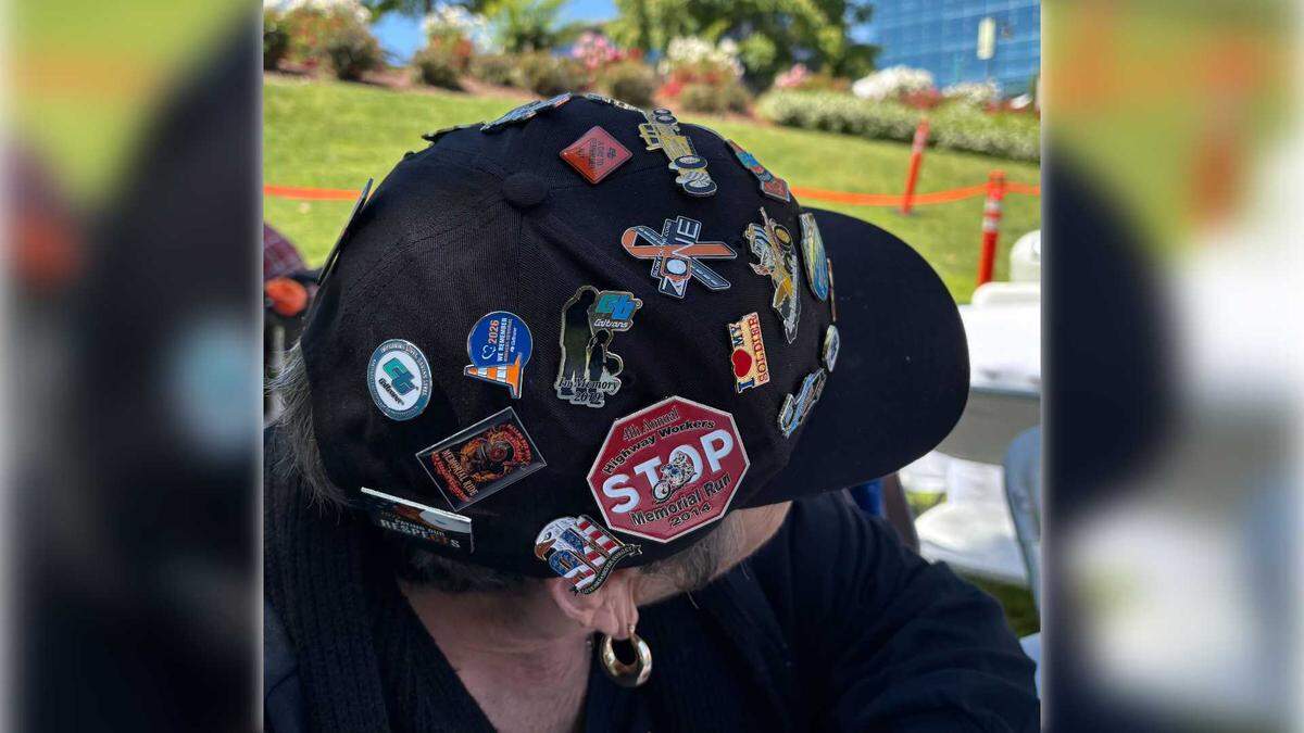 Christine Thome, 79, of Walnut, shows her hat decorated with pins from previous Caltrans workers memorial events at the 2026 event on April 23, 2026 in West Sacramento. Thome's husband died after he was struck by a vehicle on a Caltrans worksite in 1993.