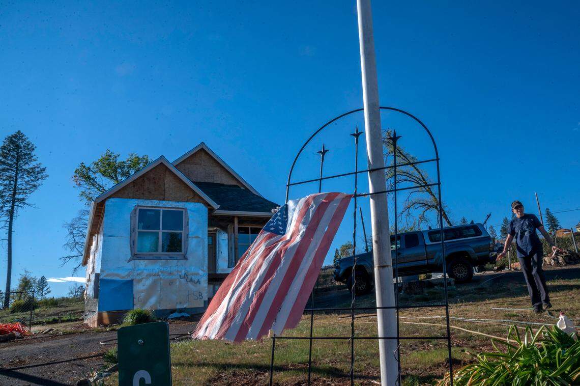 A tattered American flag blows in the wind as Sharon O’hara gardens on March 9, in front of her home that was never completed by Cubic Quarters In Paradise.