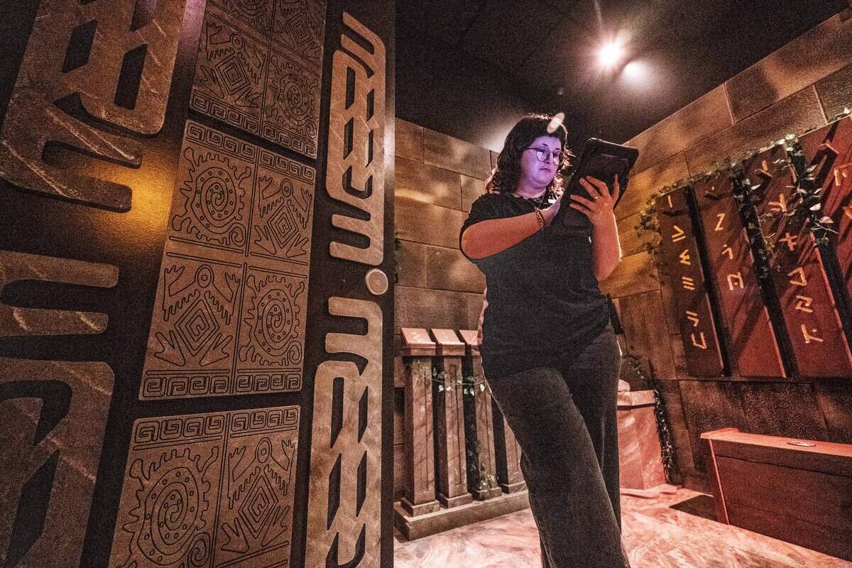 Cha Wally-Bowser, a game master at Escapology, uses her tablet to control the “Lost City” room during the venue's grand opening at Downtown Commons on Wednesday.
