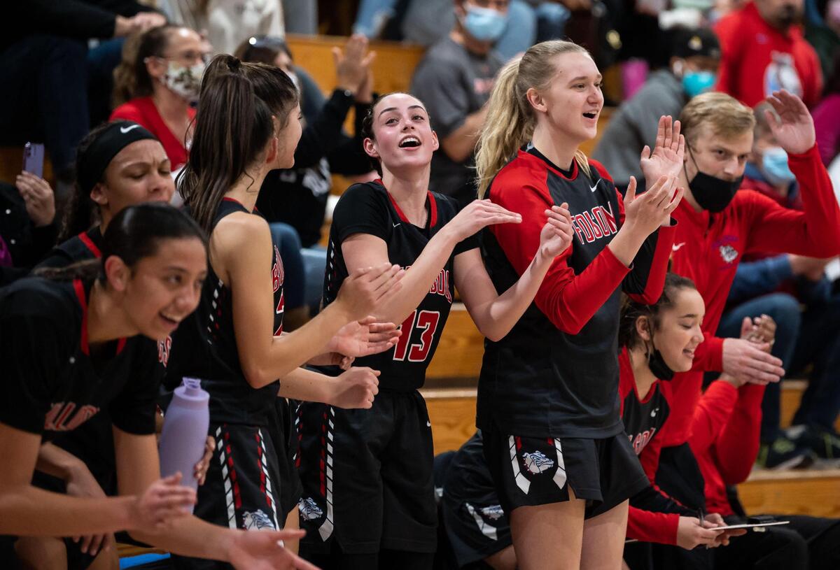 The Folsom bench, including Folsom guard Ava Rawlins (13), center, and a section of traveling fans cheer on their team as they play against hosting Laguna Creek during the fourth period of their 98-59 rout at the high school girls basketball game Friday in Elk Grove.
