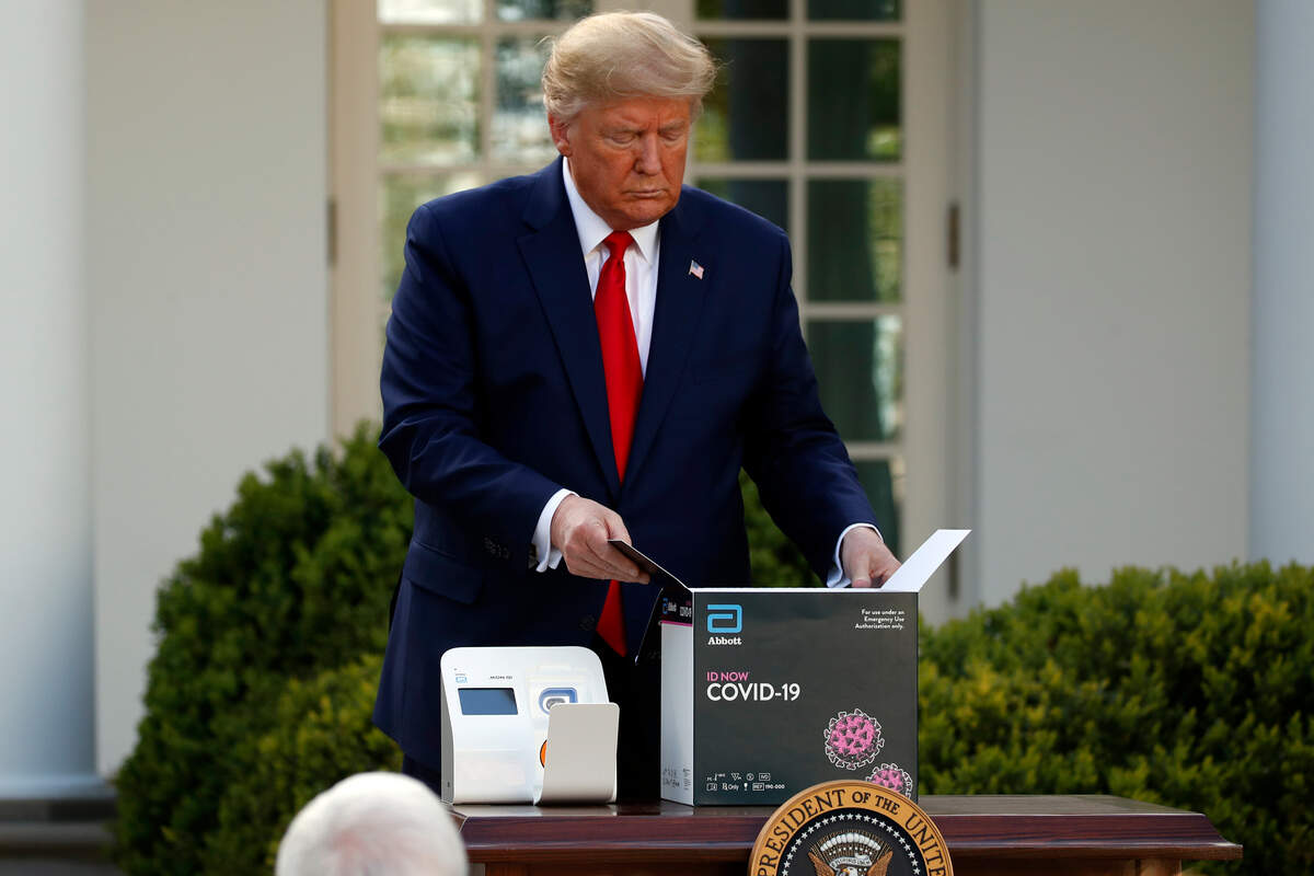 President Donald Trump opens a box containing a 5-minute test for COVID-19 from Abbott Laboratories as Stephen Hahn, commissioner of the U.S. Food and Drug Administration speaks about the coronavirus in the Rose Garden of the White House, Monday, March 30, 2020, in Washington. (AP Photo/Alex Brandon)