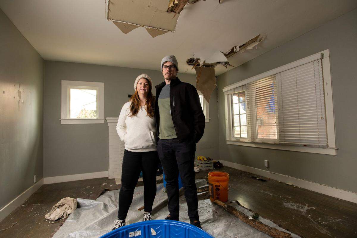 Molly O’Keefe and Hunter Parnell stand in their damaged living room in Curtis Park on Wednesday. A 100-foot tree fell in their front yard, crashing down on their roof on Jan. 7, during one of many storms that hit the area earlier this month.