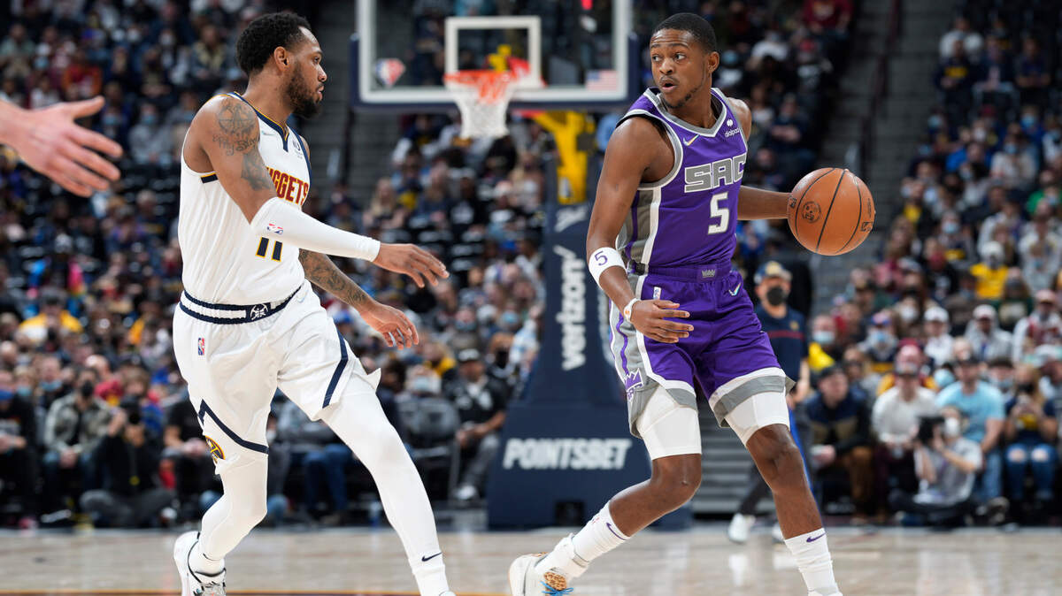 Sacramento Kings guard De’Aaron Fox, right, looks to pass the ball as Denver Nuggets guard Monte Morris defends during the first half of an NBA basketball game Friday, Jan. 7, 2022, in Denver. (AP Photo/David Zalubowski)