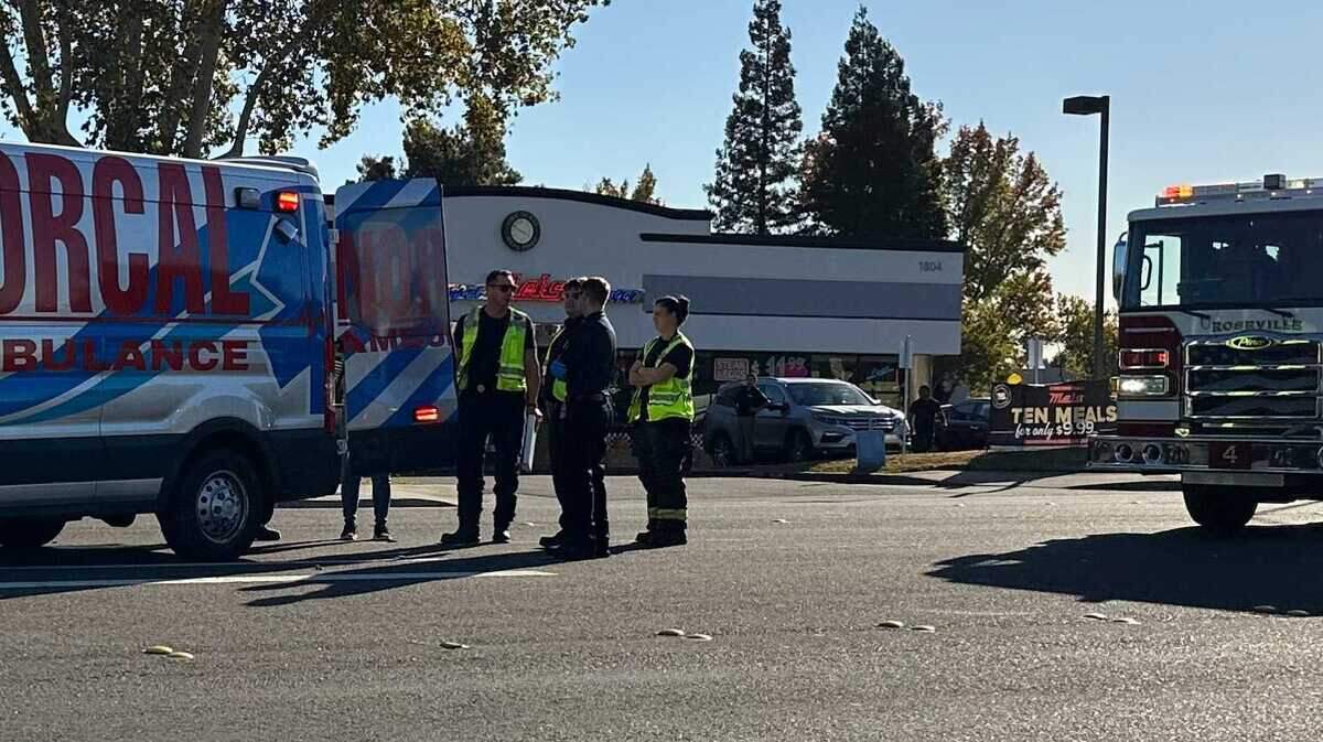 Paramedics and firefighters talk Tuesday before transporting a bicyclist who was struck on Douglas Boulevard and later died from their injuries.