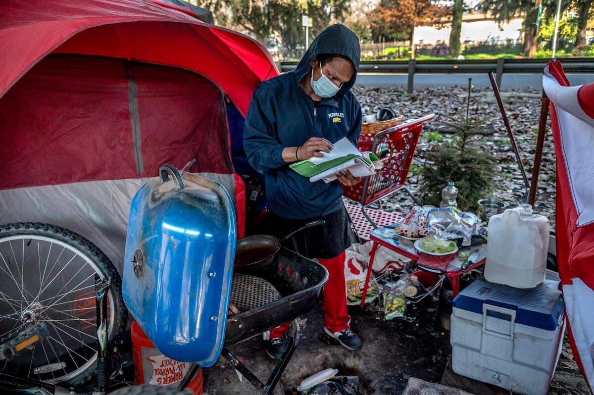 Timell Brown searches for her Housing Choice Voucher among paperwork and housing applications outside her tent. She is worried the voucher will expire before she can find housing. She said she has applied for 31 apartments and has been denied by all of them.