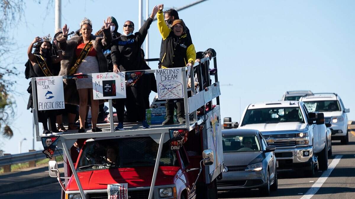A truck carries a platform filled with people celebrating Martin Luther King Jr. Day as part of a #ReclaimMLK Day car caravan on Monday, Jan. 18, 2021 in Sacramento.