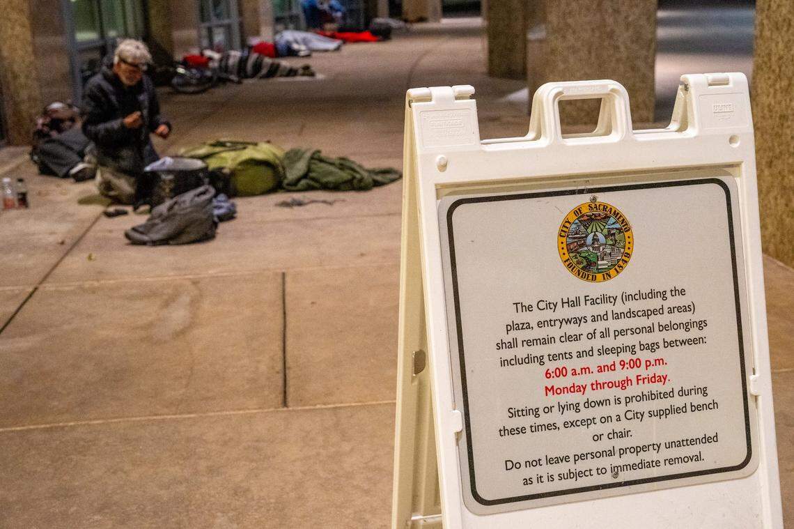 Signage in front of Sacramento City Hall could become obsolete if Mayor Kevin McCarty’s proposal to prohibit the homeless from sleeping overnight outside City Hall is approved. In the background, Randy Horn, 72, ties his belongings together before sleeping in the area.