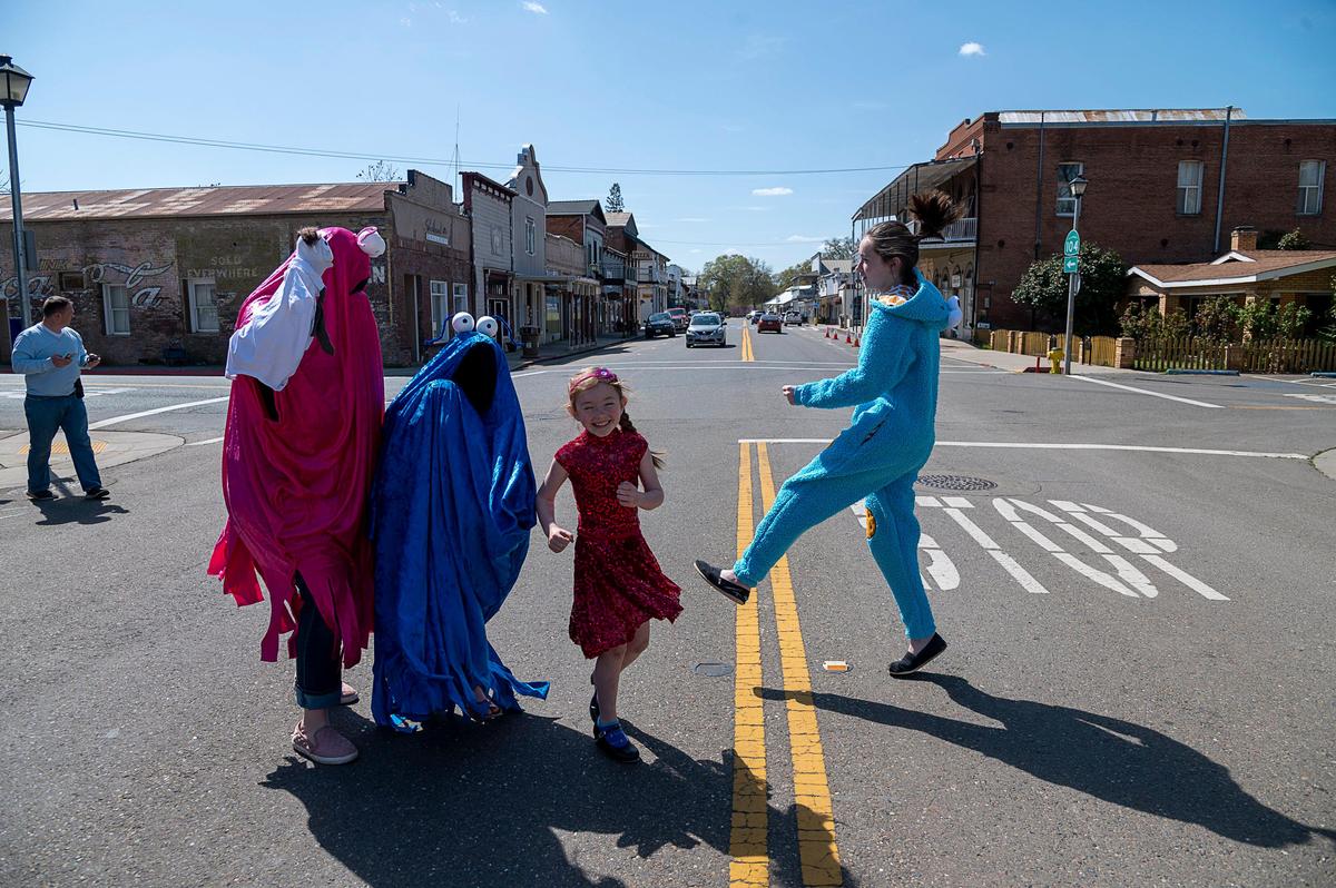 Russ Harmon, right, films wife Darci, in red Muppet costume, and daughters Bridget, 9, left, Clara, 6, and Alexis, 16, for a video lip syncing the song “Man or Muppet” from the Muppet movie on Friday, March 27, 2020, while on a walk in Ione. Amador County residents have cut their average distance traveled by more than 45% during the coronavirus crisis, according to a review of smartphone data.