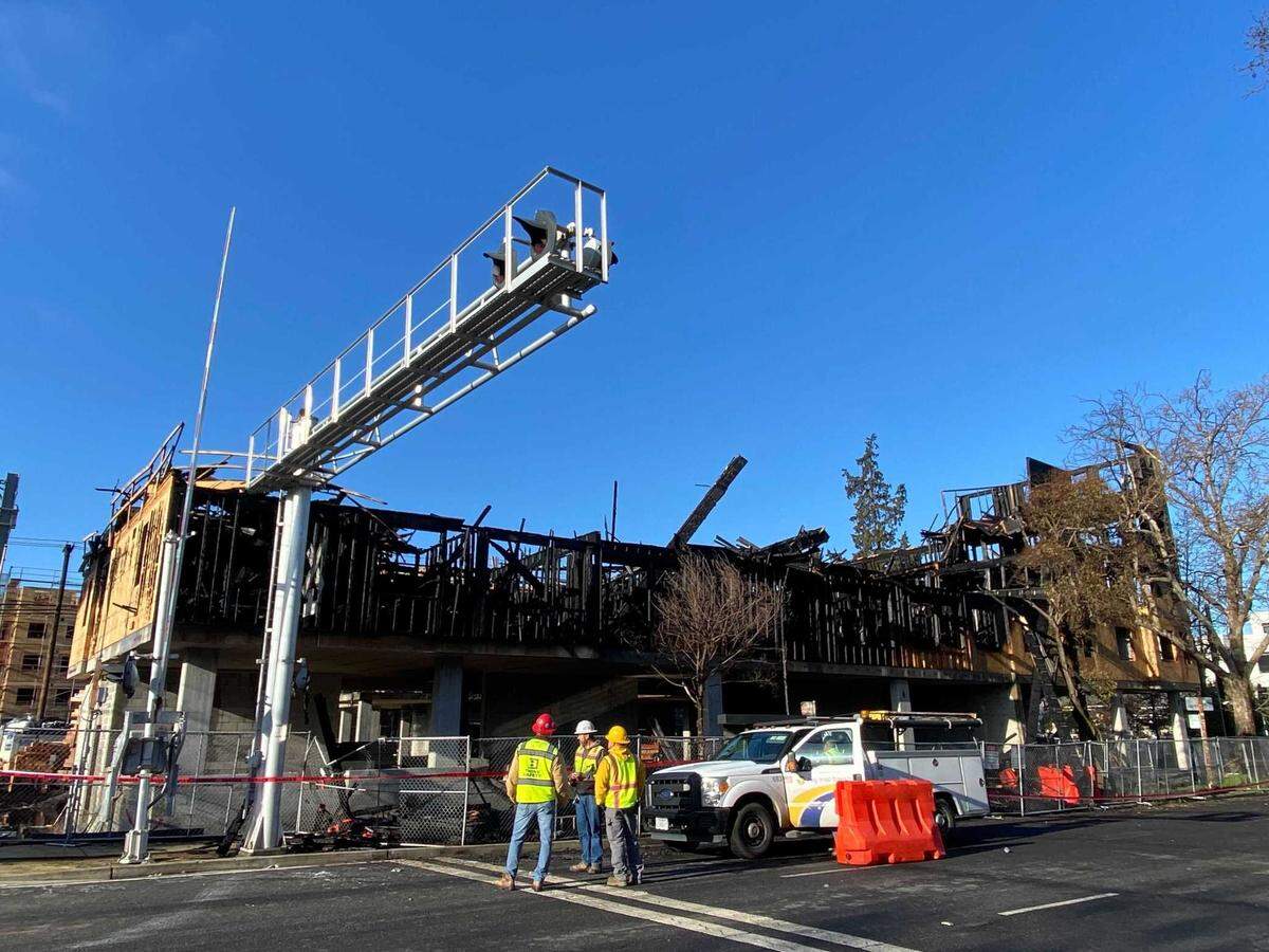 Construction personnel look over the ruins of a five-story housing complex under construction on 19th Street between Broadway and X Street in Sacramento on Tuesday, March 26, 2024. The building was damaged by a three-alarm fire overnight.