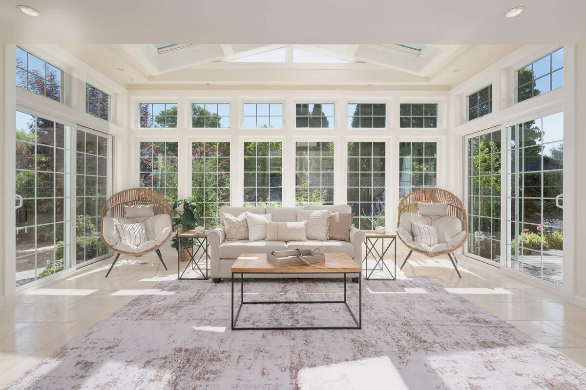 A beautiful orangerie, or sunroom, with floor- to-ceiling windows and skylights sits brings the outdoors inside.