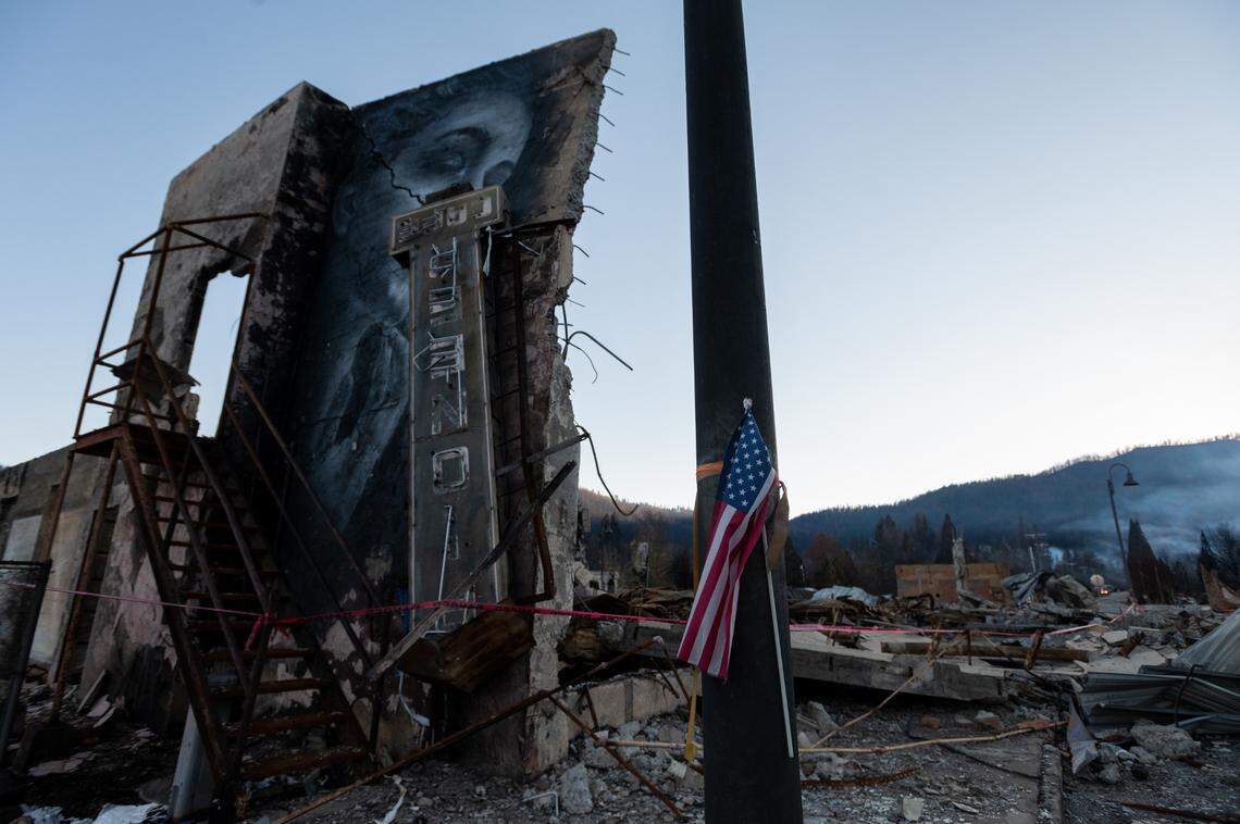 A sign for the Pioneer Cafe obscures a mural as it dangles from the remains of the Sierra Lodge, destroyed in the Dixie Fire over the summer, on Dec. 3 in Greenville. The fire destroyed most of the small town in Plumas County.