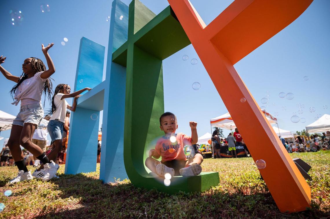 Liam Michael, 2, of Sacramento, admires the bubbles floating around letters promoting the H@ck the Park outdoor festival, organized by the non-profit Square Root Academy, on Saturday at Maple Park in Sacramento.