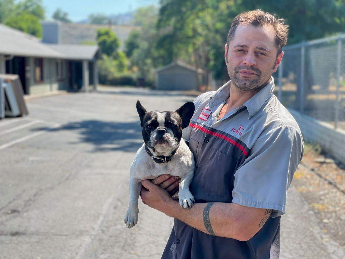James “Mac” Benton and his dog PeeWee stand outside a hotel in Yreka on Tuesday after narrowly escaping the McKinney Fire.