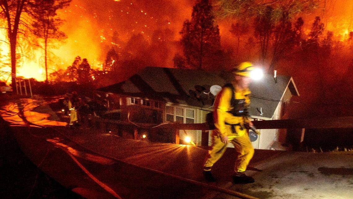FILE - In this Friday, Aug. 21, 2020, file photo, Firefighters protect a home in the Berryessa Estates neighborhood of unincorporated Napa County, Calif., as the LNU Lightning Complex fires burn. (AP Photo/Noah Berger, File)
