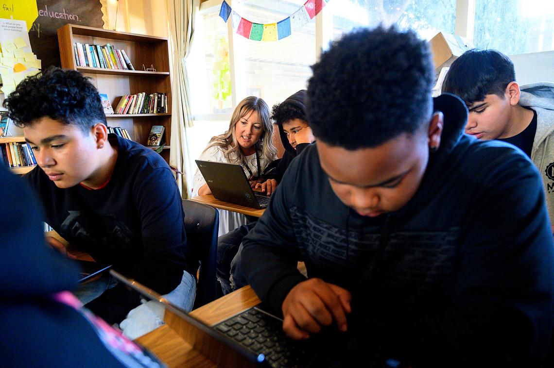 Teacher Kim Minugh helps Darrion McGlother in her classroom at Encina Preparatory School on Thursday, November 7, 2019 in Sacramento. Students, left to right, C.J. Brown, Eric Wilson and Diego Villegas complete an assignment on laptop computers.