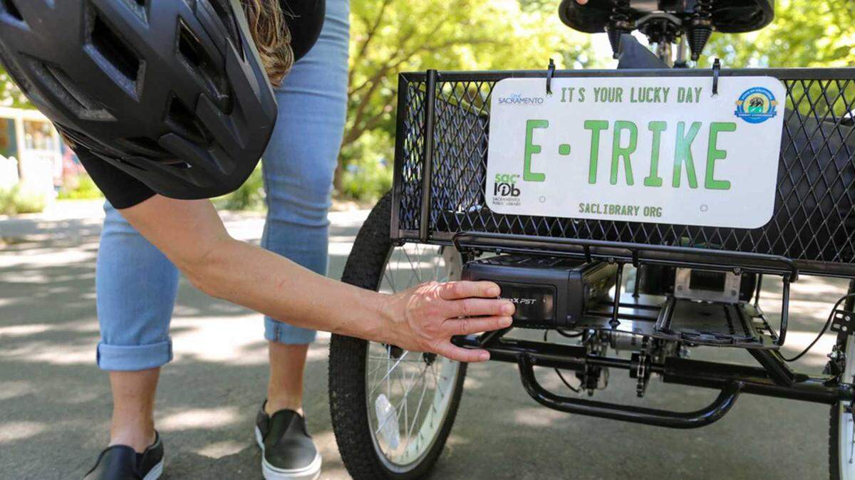 A library patron checks out an electric tricycle at a branch of the Sacramento Public Library. Four locations are now offering free e-bike and e-trike loans to adults with a library card.