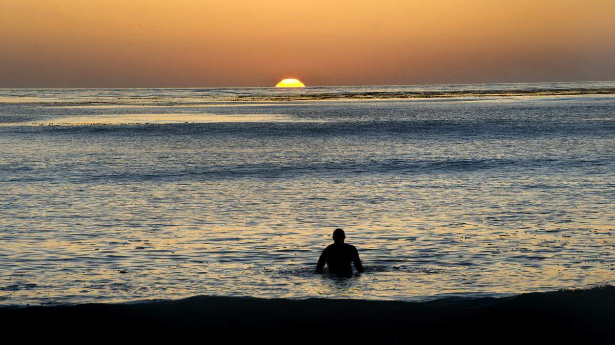 A surfer watches the sun set from the ocean at Carmel-by-the-Sea in September 2010.