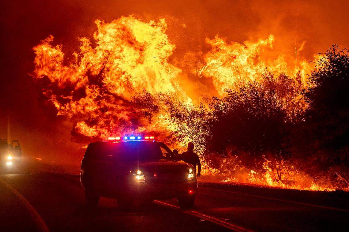 Flames lick above vehicles on Highway 162 as the Bear Fire burns near Oroville, Calif., on Wednesday, Sept. 9, 2020. The blaze, part of the lightning-sparked North Complex, expanded at a critical rate of spread as winds buffeted the region.