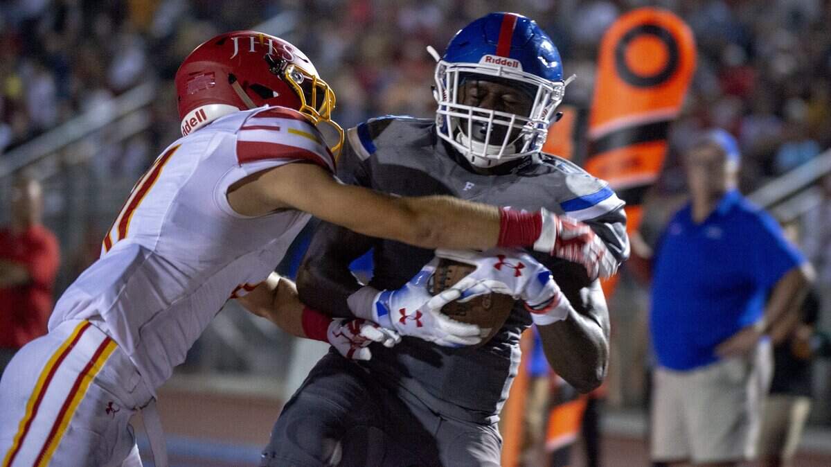 Folsom Bulldogs’ Daniyel Ngata (4) catches a seven-yard touchdown pass while defended by Jesuit Marauders’ Spencer Vigil (11) on Aug. 24, 2018.