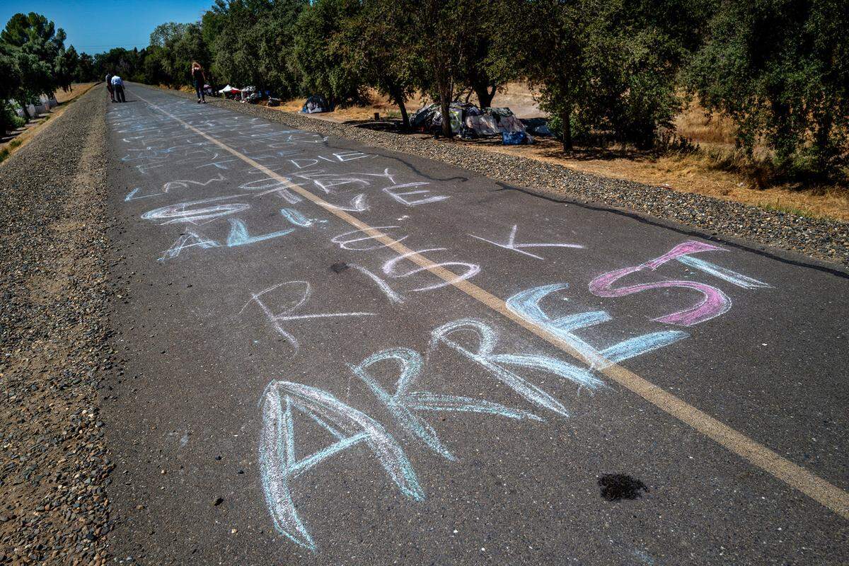 A charcoal message on the bike path made Wednesday by Joyce Williams and her partner Sharon Jones, who live in the American River Parkway along the levee off Railroad Drive in Sacramento, pleads for more help for the homeless.