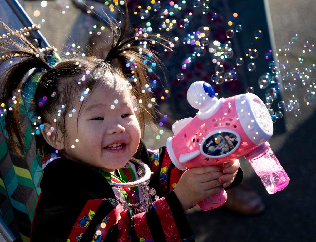 Heart Vue, 2, of Sacramento, plays with a new bubble gun she got as thousands celebrate the Sacramento Hmong New Year festival Saturday.