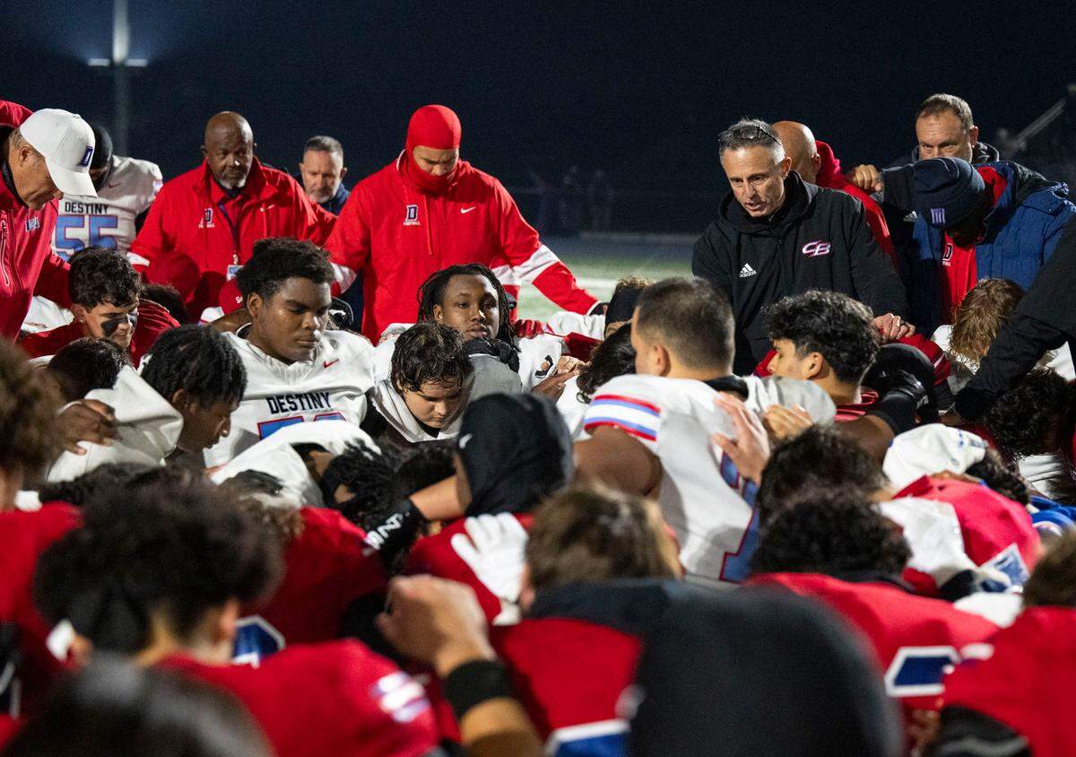Christian Brothers and Destiny Christian players join together at midfield for a postgame prayer led by Falcons assistant coach Jon Scriven after the Sac-Joaquin Section Division III quarterfinal game on Friday, Nov. 15, 2024, in Sacramento.