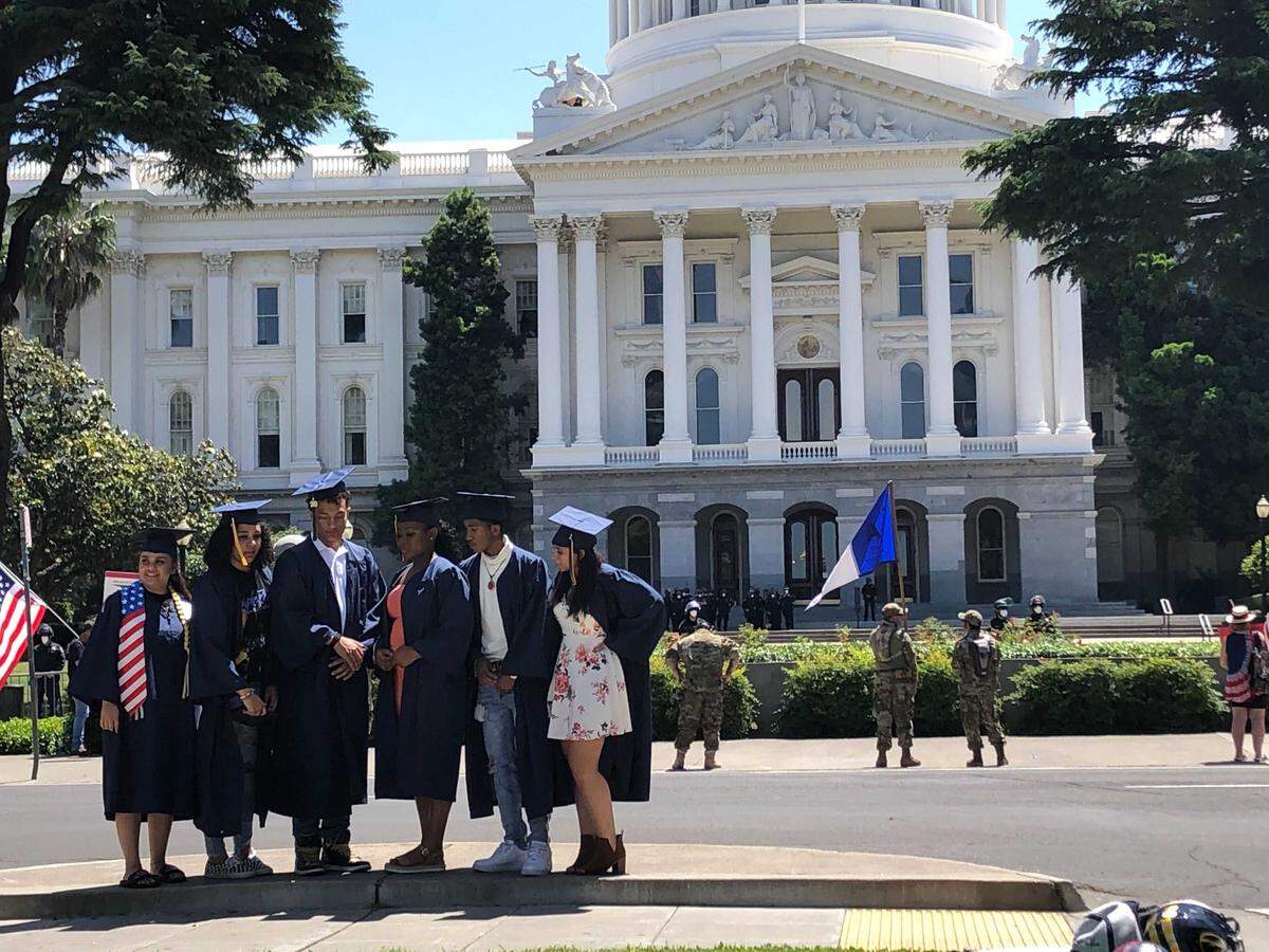 Seniors from Inderkum High School in Sacramento pose Saturday, May 9, 2020, in front of the state Capitol in Sacramento, Calif. Dozens of families took pictures Saturday as demonstrators, some in militia fatigues, descended on the area around the Capitol to protest California Gov. Gavin Newsom’s coronavirus stay-at-home order.