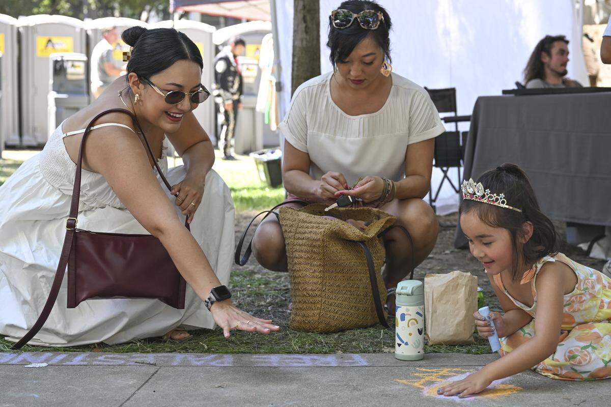 Sofia Tornatore, right, shows her family her chalk drawing during Chalk It Up art festival at Fremont Park in Sacramento on Sunday.