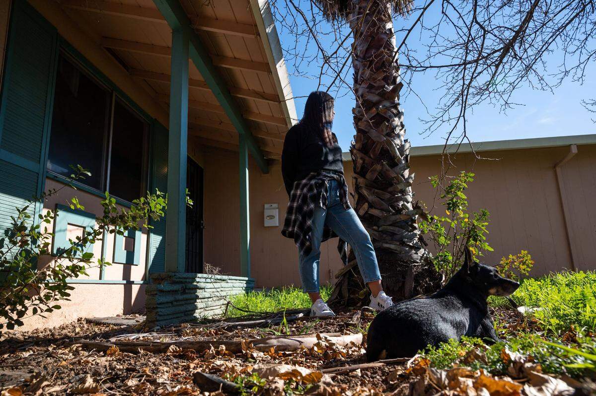 Rachel Walker and her dog, Yoda, spend time in the front yard in January at the Rancho Cordova rental where the single mother has lived with her children for five years. She is being evicted after her longtime landlords were murdered in Fiji. “It’s probably the most stable place that we’ve been, just being an ex-military family,” she said.
