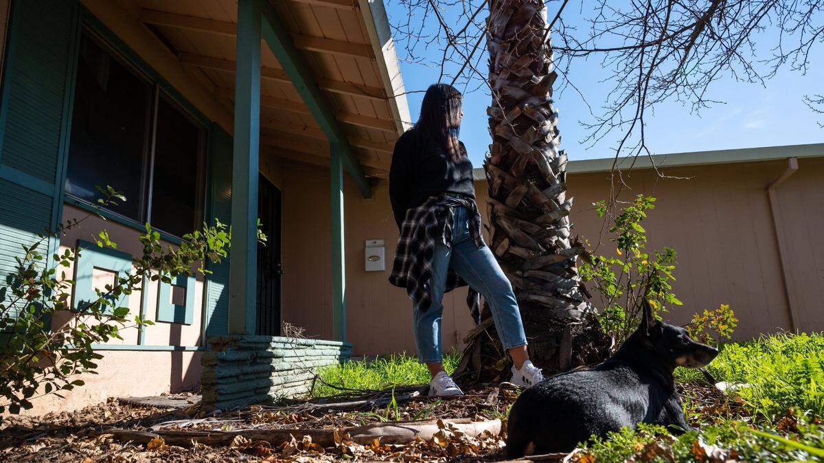 Rachel Walker and her dog, Yoda, spend time in the front yard Saturday, Jan. 29, 2022, at the Rancho Cordova rental where the single mother has lived with her children for five years. She’s being evicted after her longtime landlords were murdered in Fiji. “It’s probably the most stable place that we’ve been, just being an ex-military family,” she said.