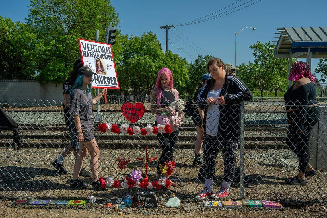 Erika Pringle, center, gazes down at painted rocks that she and her friends cemented at the base of a fence near the light rail station where her brother, Andrew Pringle, was struck by a motorist while crossing Folsom Boulevard in Rosemont during a memorial ceremony on April 23, two years after his death.