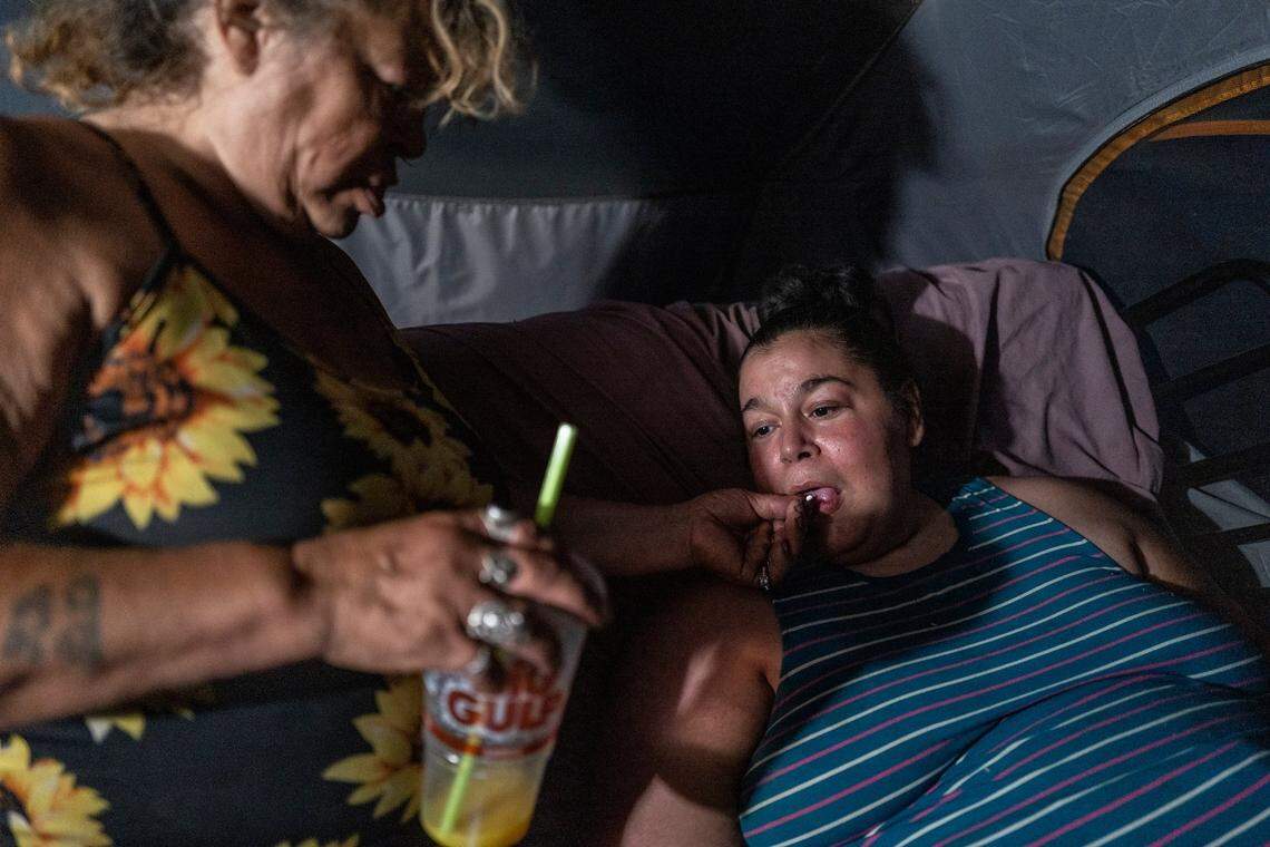 Holly Porter, 40, who suffers from quadriplegia who can’t find housing or healthcare workers to come to her tent along the American River, depends on mother Deborah Casillas to give her medicine in October in her tent while it was located near the American River, after the Colfax Avenue camp was swept. She later moved back to that location.