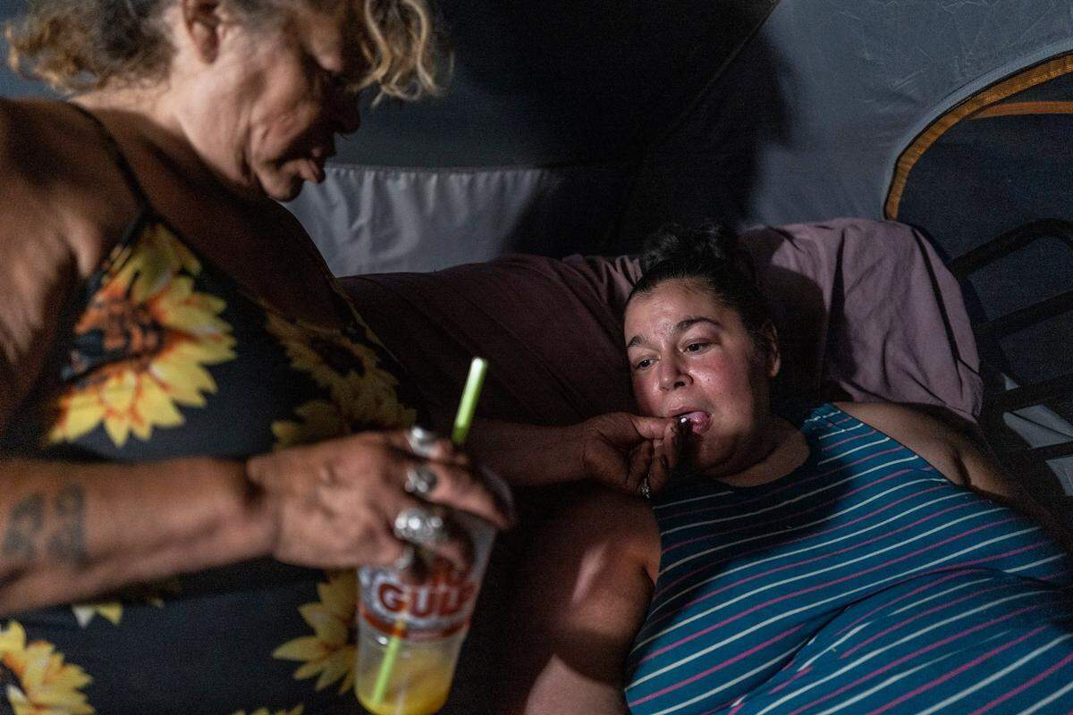 Holly Porter, 40, who suffers from quadriplegia who can’t find housing or healthcare workers to come to her tent along the American River, depends on mother Deborah Casillas to give her medicine in October in her tent while it was located near the American River, after the Colfax Avenue camp was swept. She later moved back to that location.